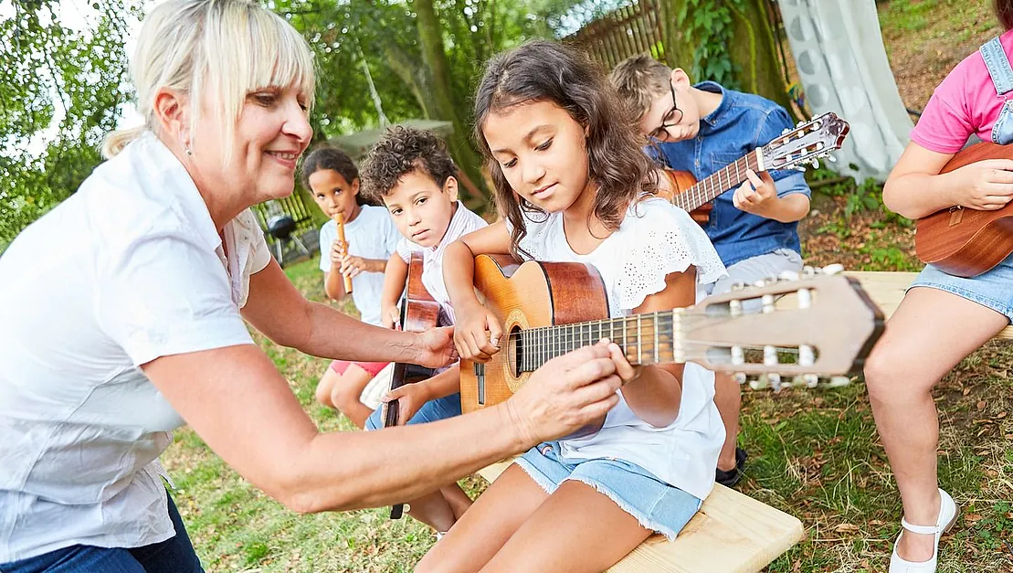 profesora de música dando clase de guitarra a niños